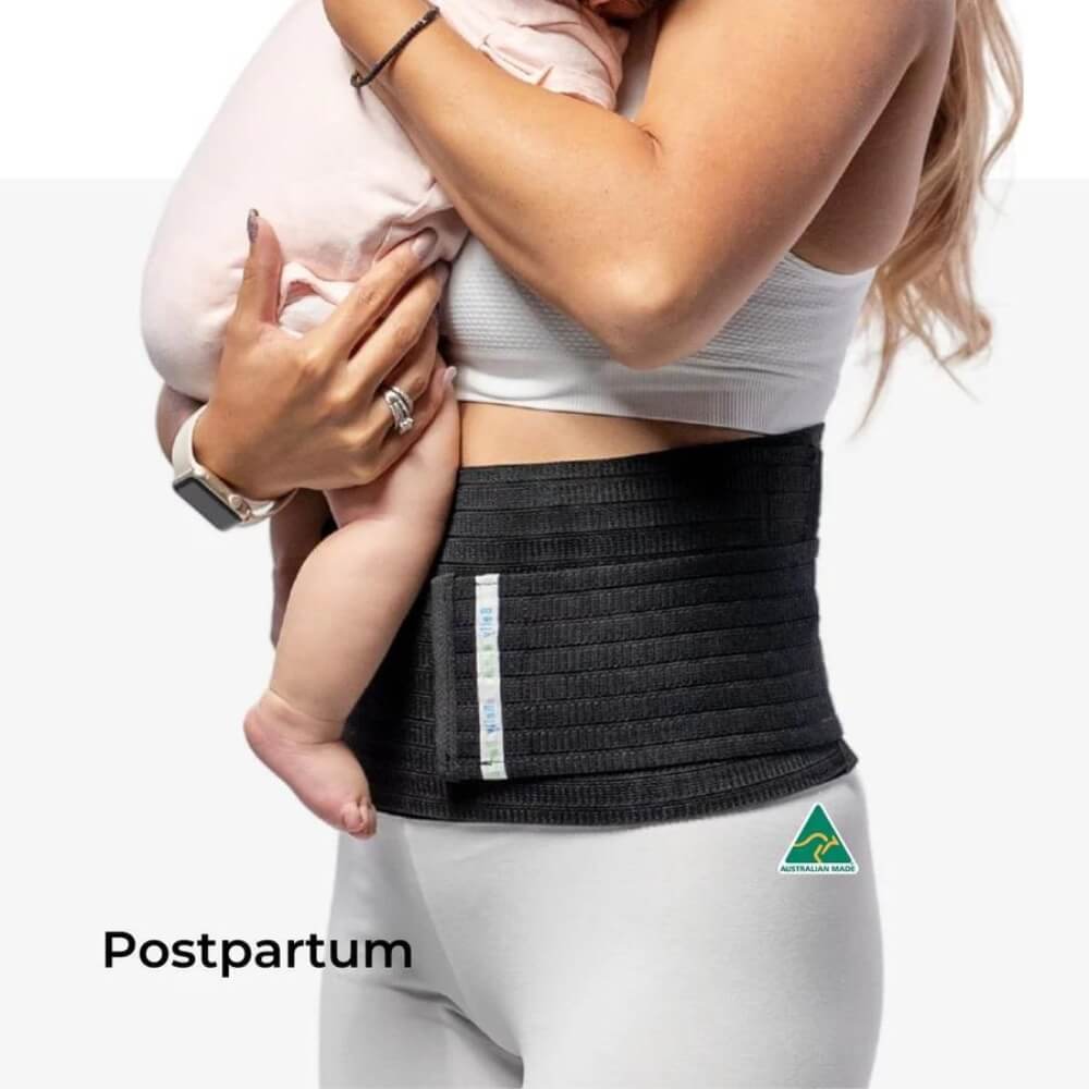 A woman wearing a snug black **3-in-1 Belly Band for Pregnancy, Postpartum, C-section** from **Belly Bands** holds a baby. She is dressed in a white sports bra and leggings. A label on the band and a green logo on the leggings are visible. "Postpartum" is written in the lower-left corner of the image.