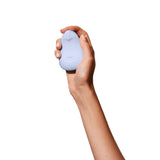 A hand holds the Dame Pom, an external flexible vibrator from the brand Dame. This small, light blue, egg-shaped object is crafted from medical-grade silicone and features a smooth texture with a pointed tip. Its ergonomic design stands out against the plain white background, highlighting its elegant form.