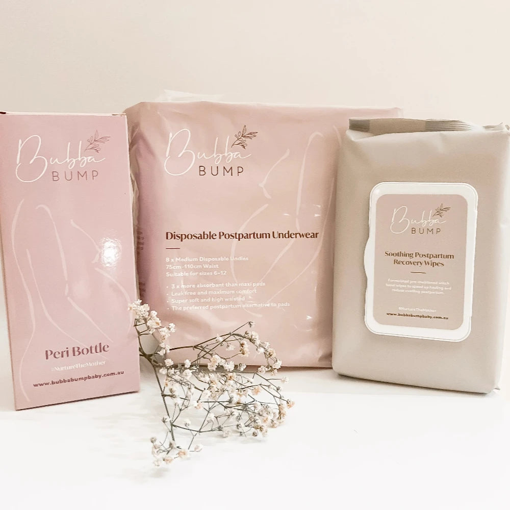 The Bubba Bump Peri Care Bundle includes a Peri Bottle, disposable postpartum underwear, and soothing Witch Hazel wipes. Delicate white baby's breath flowers are arranged in front to add an elegant touch.