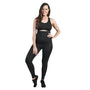 A woman smiles confidently while posing in black activewear against a white background. She is wearing an SRC Postpartum Recovery Leggings and a black sports bra, with one hand on her hip. Exhibiting both comfort and confidence, she showcases an athletic outfit from SRC Health that is ideal for postpartum recovery.