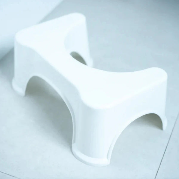 The BIEN Toilet Stool by BIEN Australia is a white plastic, ergonomic stool designed to fit around the base of a toilet, resting on a tiled bathroom floor. It features a U-shaped form and curved legs for stability, promoting natural bowel movements and potentially alleviating constipation.